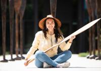 Stephanie Masterman sits outside the Burke museum holding a Tlingit cedar canoe paddle she recently carved