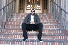 American Indian Studies student Ben Brockie sits on the steps of a campus building.