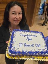 Kai holding a sheet cake that reads "Congratulations, Kai. 10 years at UW!" 