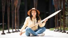 Stephanie Masterman sits outside the Burke museum holding a Tlingit cedar canoe paddle she recently carved