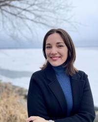 smiling person stands in front of frozen lake