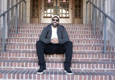 American Indian Studies student Ben Brockie sits on the steps of a campus building.