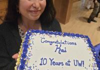 Kai holding a sheet cake that reads "Congratulations, Kai. 10 years at UW!" 
