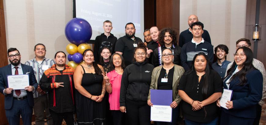 group of 19 students holding certificates and smiling at the camera